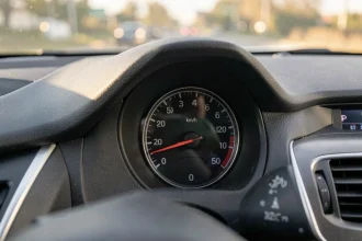 Tableau de bord de voiture montrant le compteur de vitesse à 50 km/h, équivalent de 30 mph, avec la route en arrière-plan flou